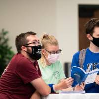 Scholars wearing masks looking at abstact books.